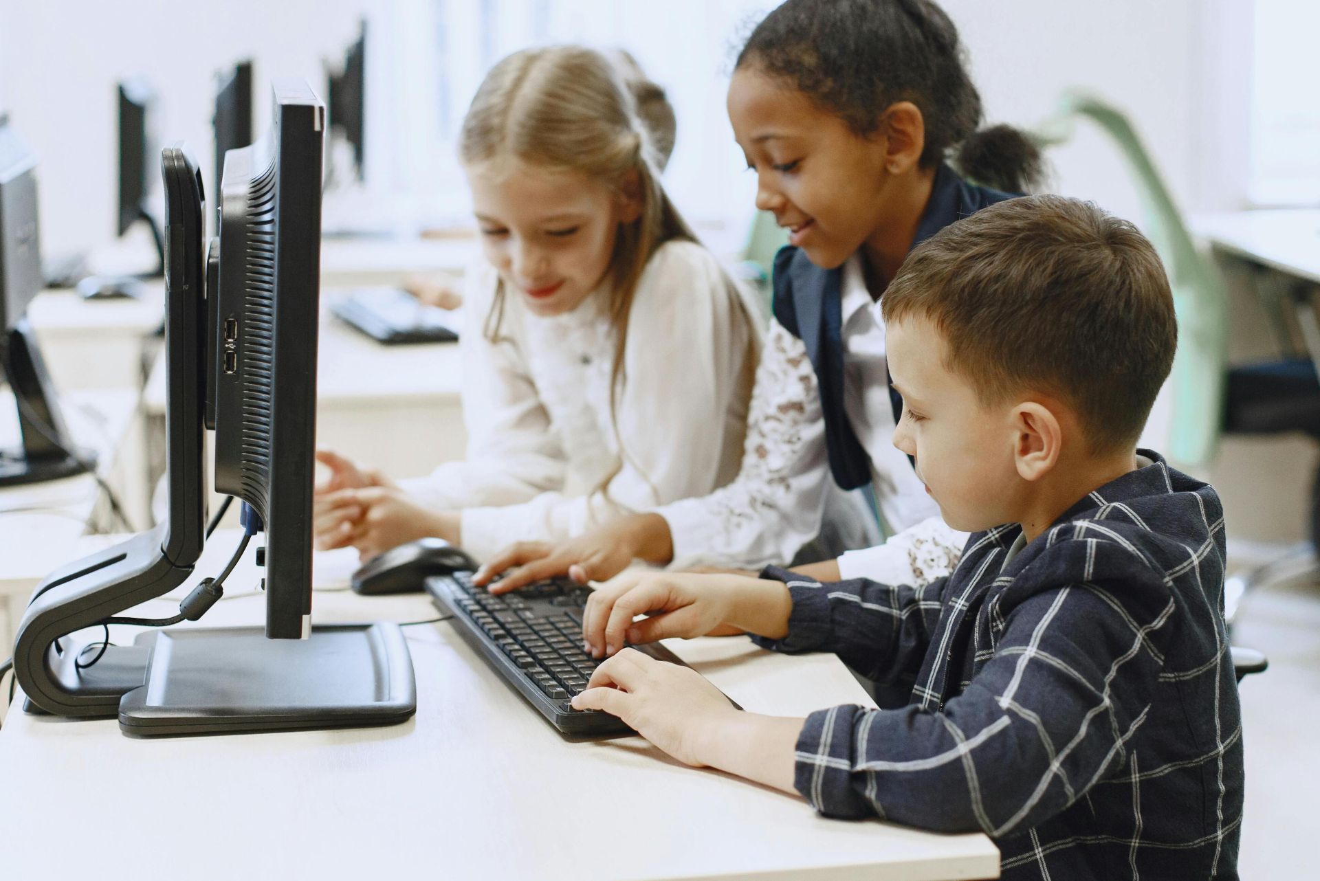 Children in a computer lab learning and collaborating on projects together.