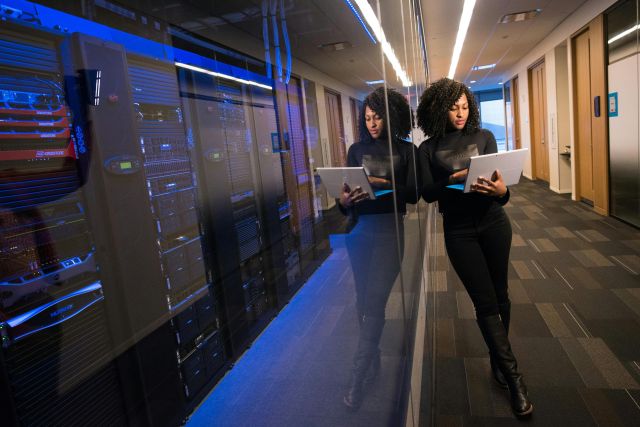 A woman using a laptop navigating a data management center in a school, small business, nonprofit, or municipality.